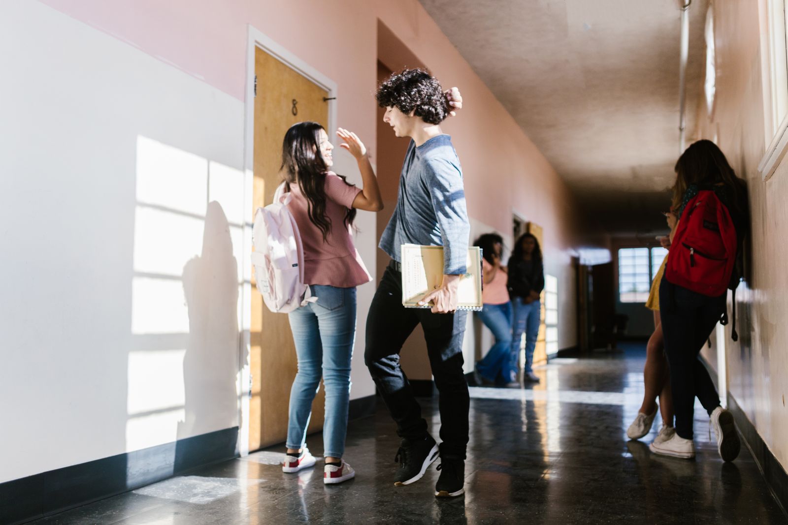 High school students casually interact in a brightly lit hallway.