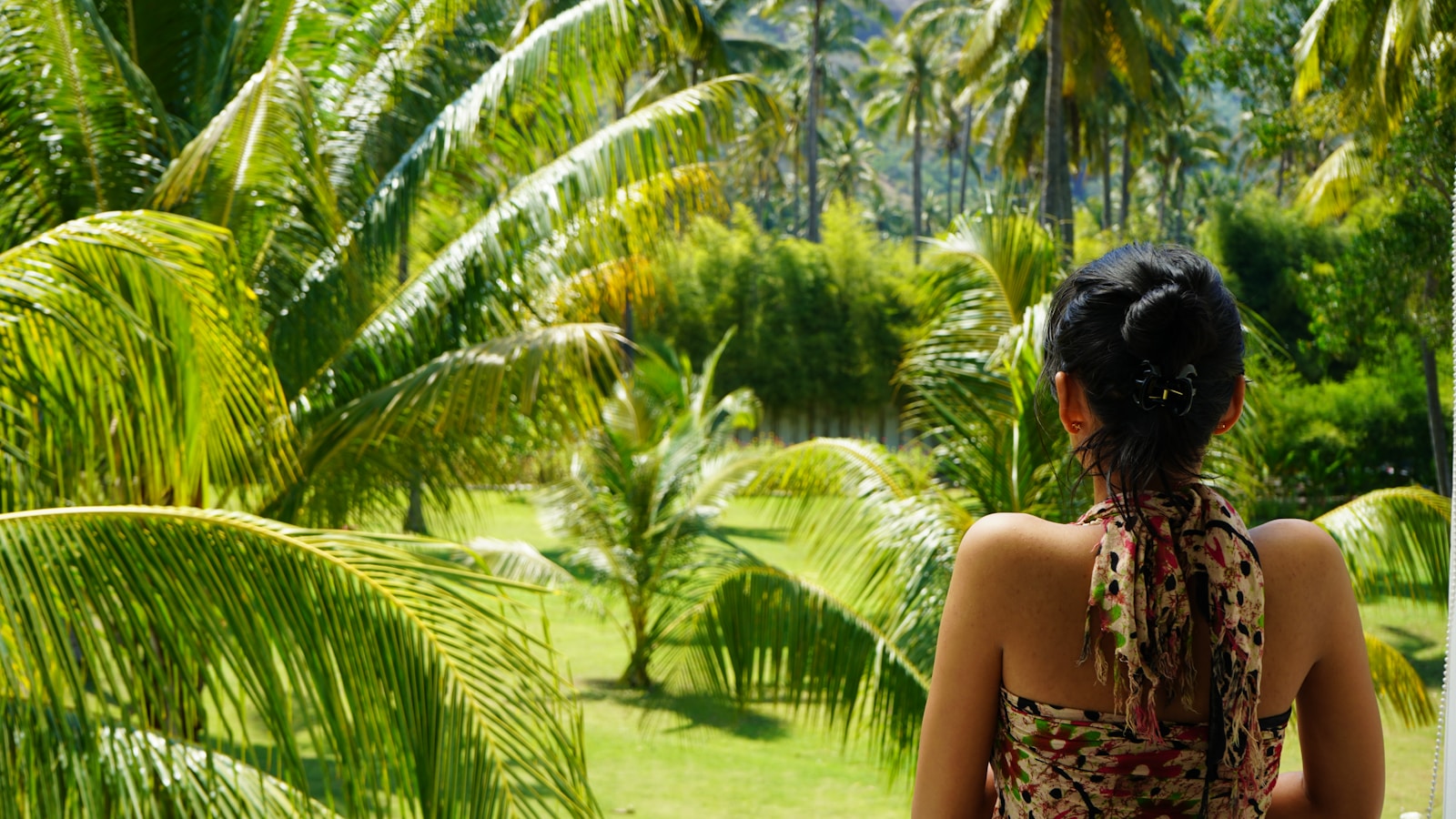 A woman looking out a window at a lush green forest