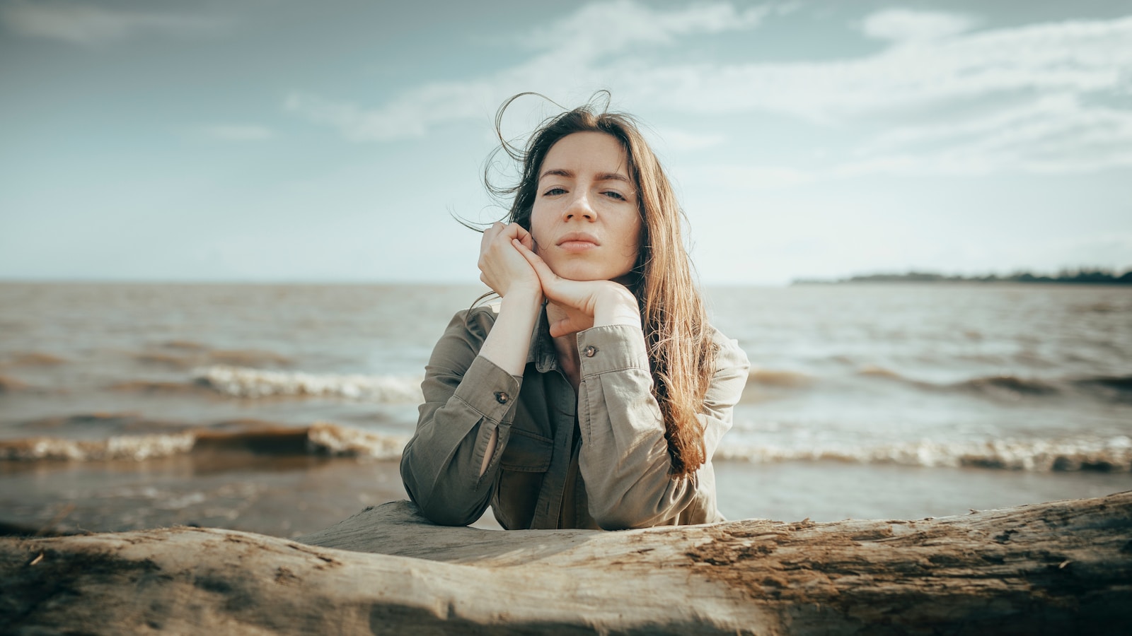 Young woman resting chin on hands by the sea