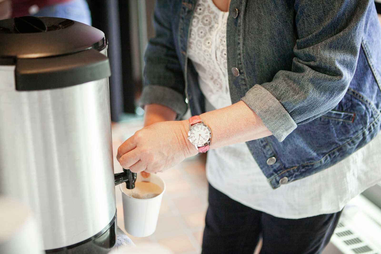 woman filling cup front jar