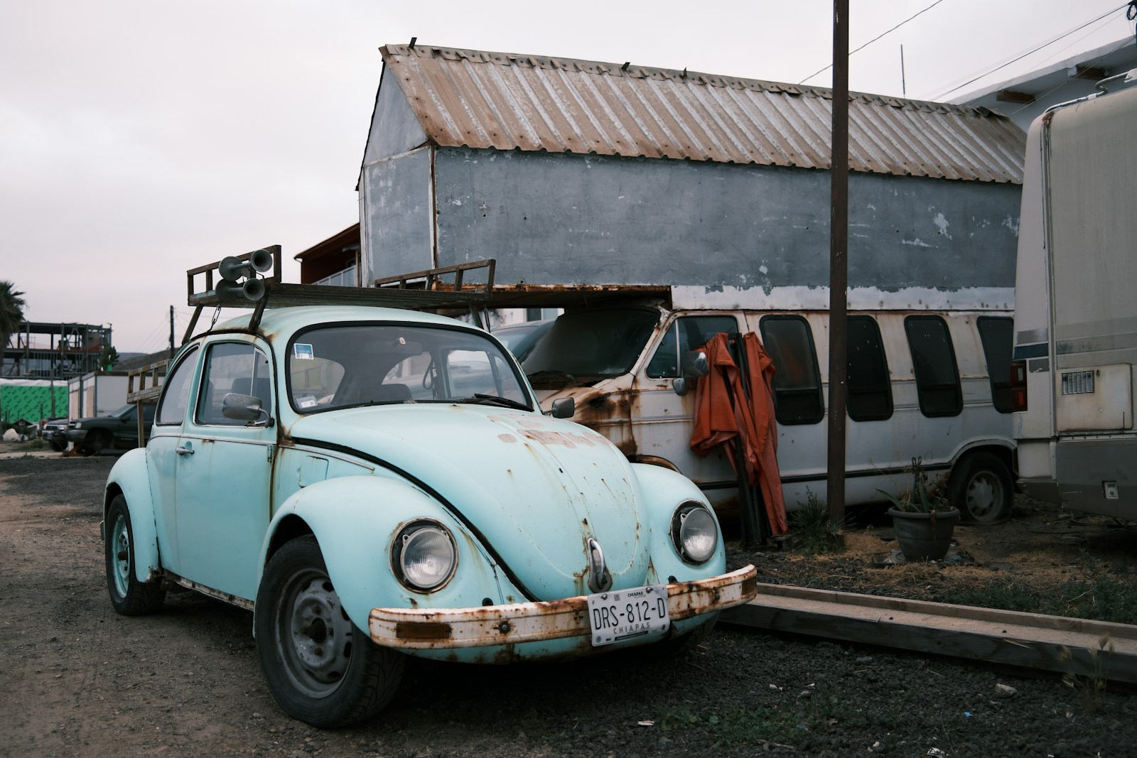 A weathered blue car is parked near a building.