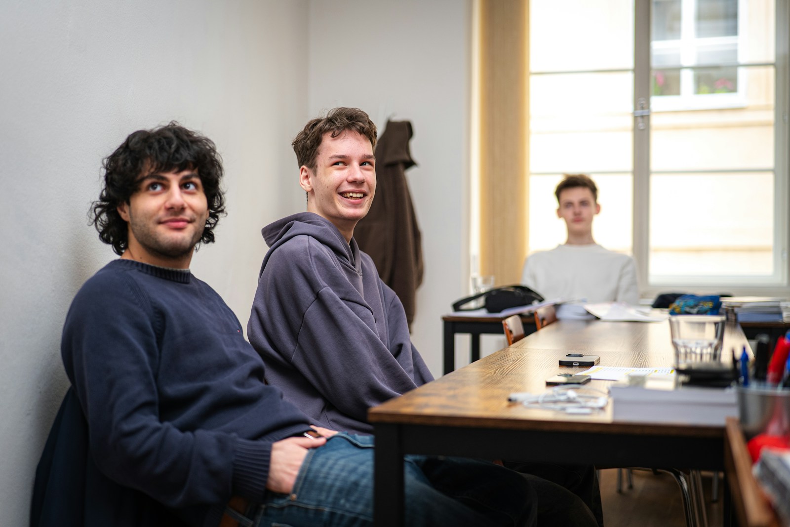 Three young men sitting at a table indoors.
