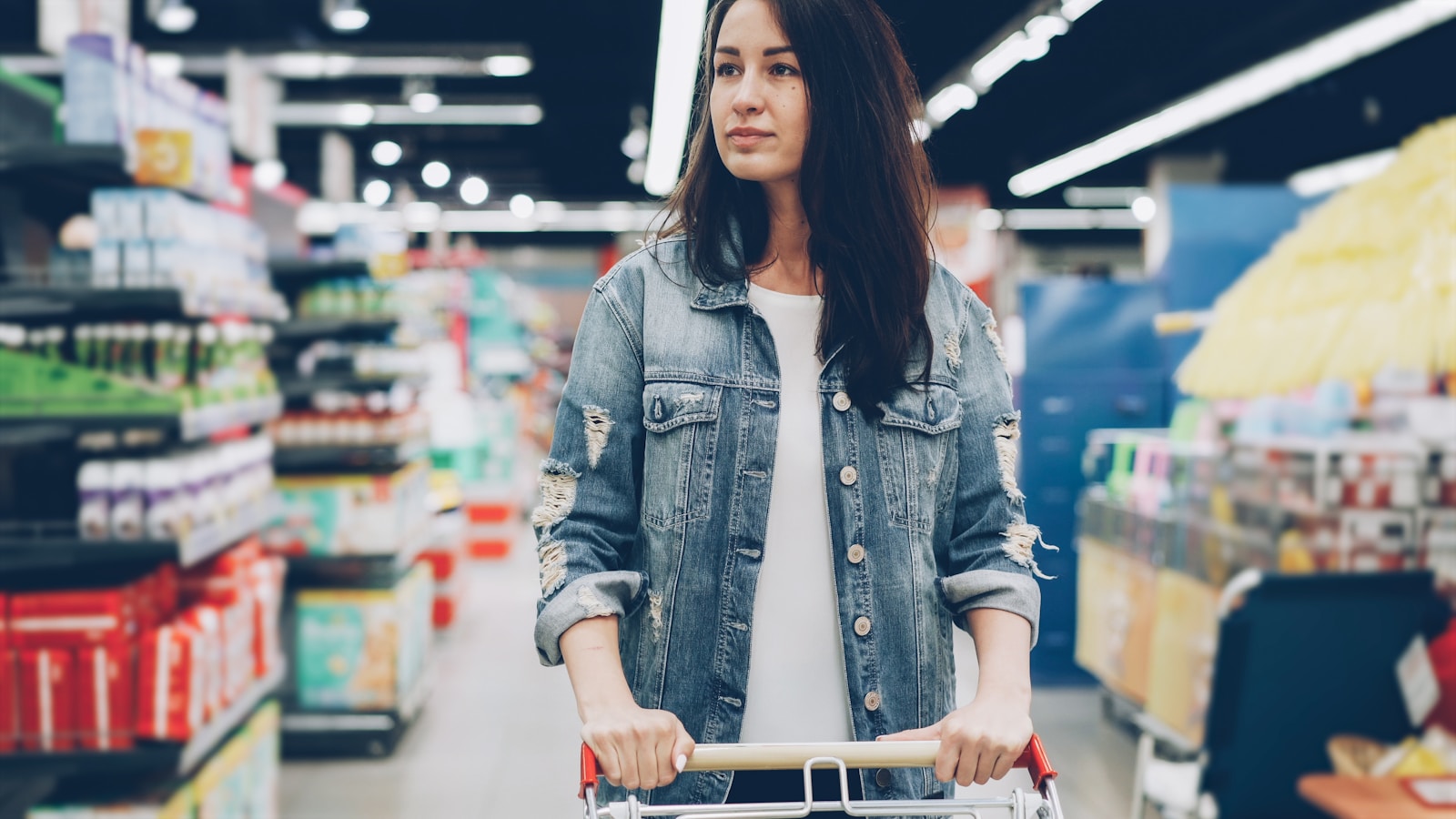 Woman pushing a cart while shopping in a grocery store.