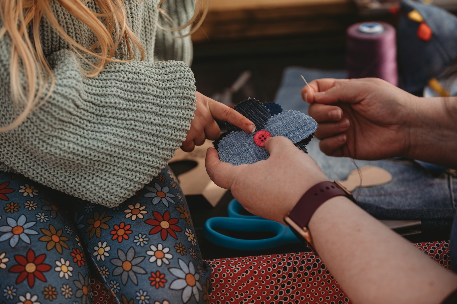 Hands crafting a denim patch with needle and thread.