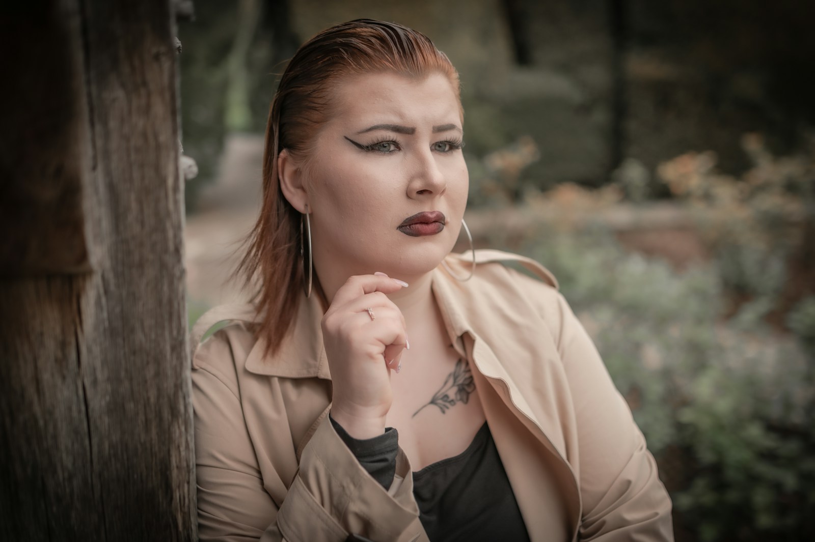 a woman with a tattoo on her neck leaning against a wall