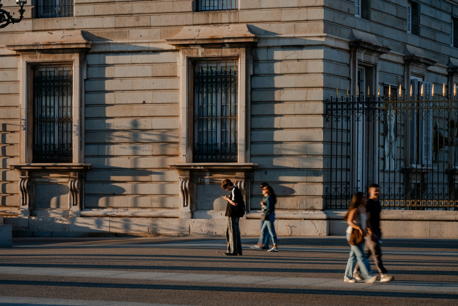 People walking past a building at sunset