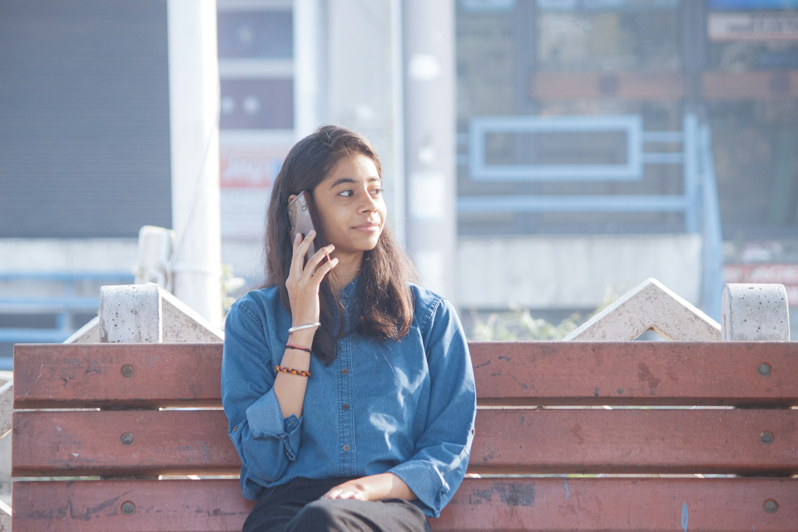a woman sitting on a bench talking on a cell phone