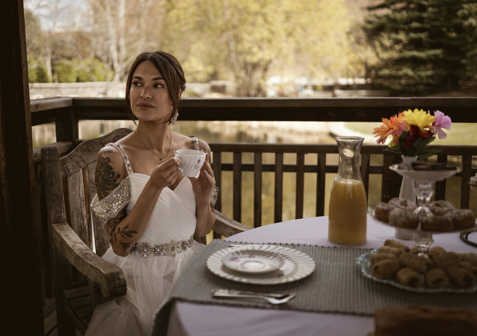 Woman in white dress enjoys tea outdoors with pastries outdoors