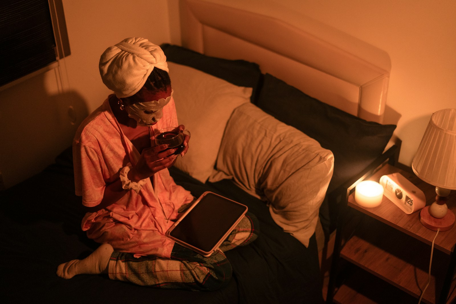Person in pajamas using a tablet on a bed.