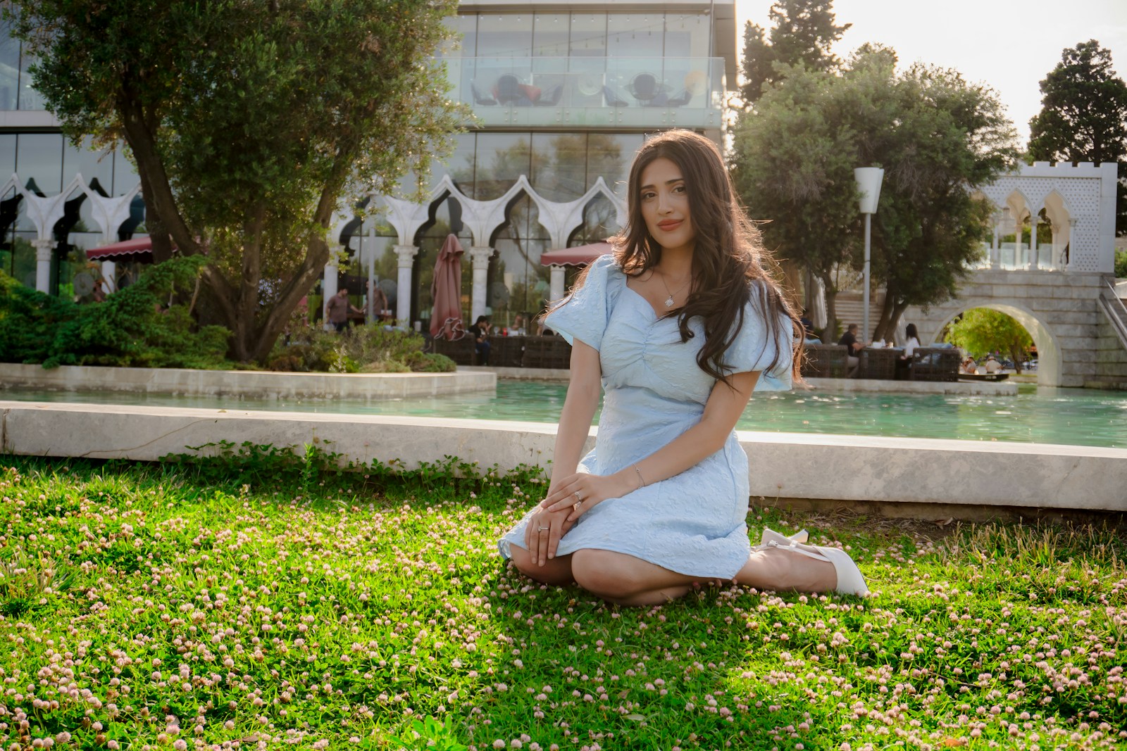 Woman in light blue dress sitting on grass