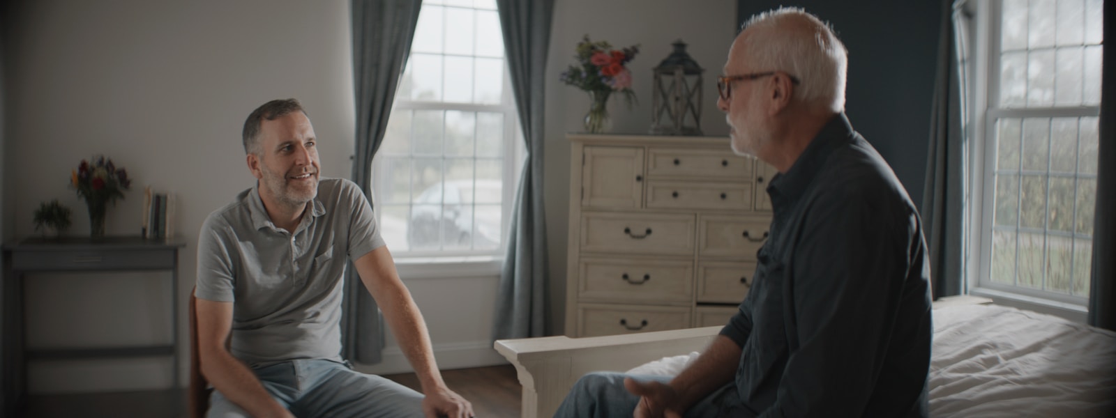 Two men talking in a warmly lit room.