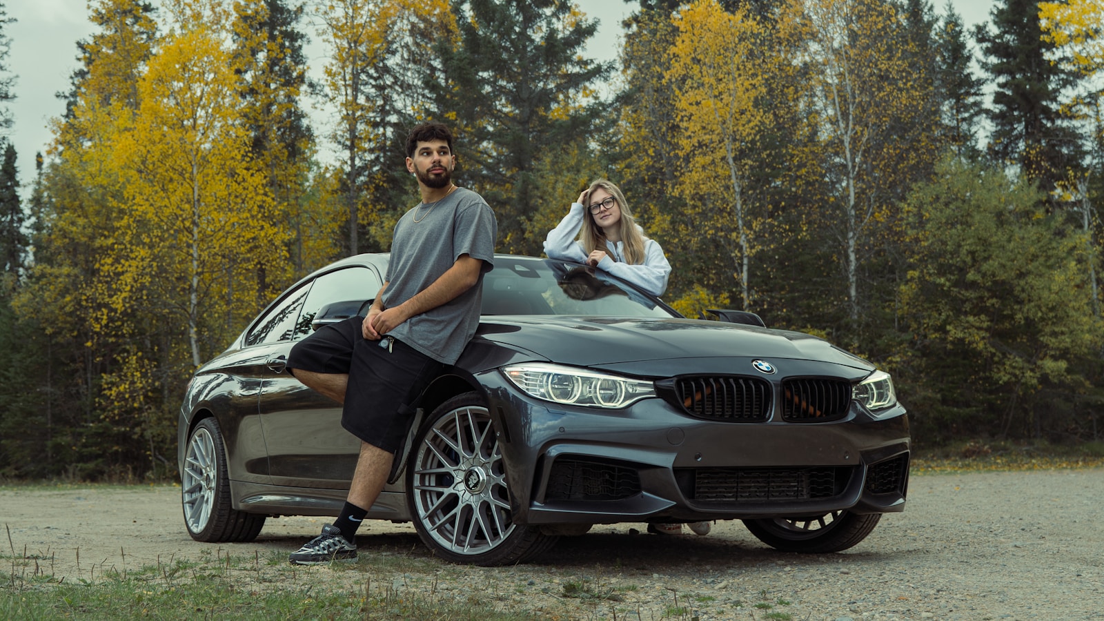 Couple posing with a car in a forest