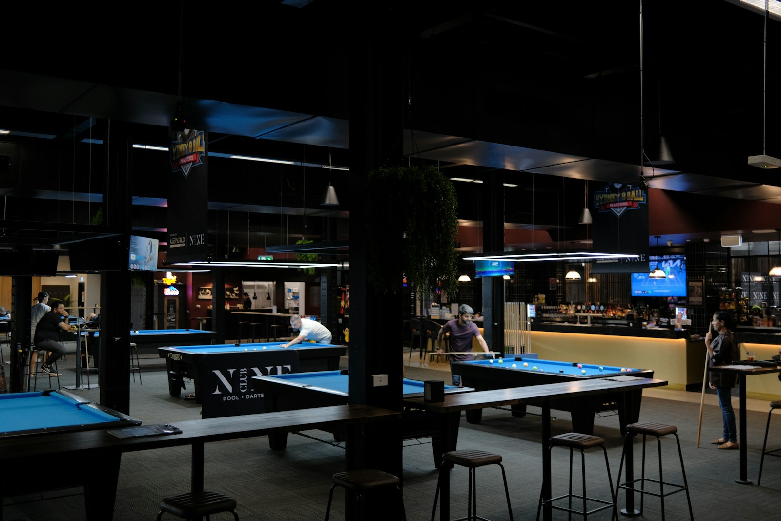 People playing pool in a dimly lit bar.