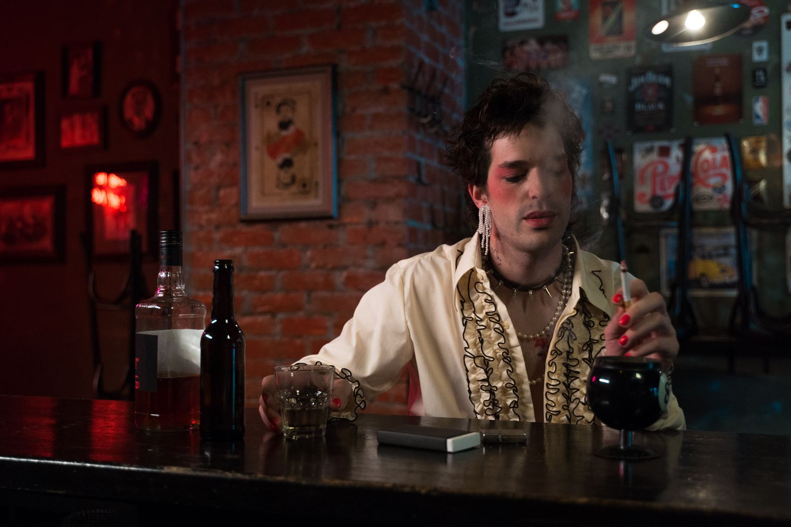A person with bold makeup enjoys beverages at a dimly lit vintage bar, exuding style and nostalgia.
