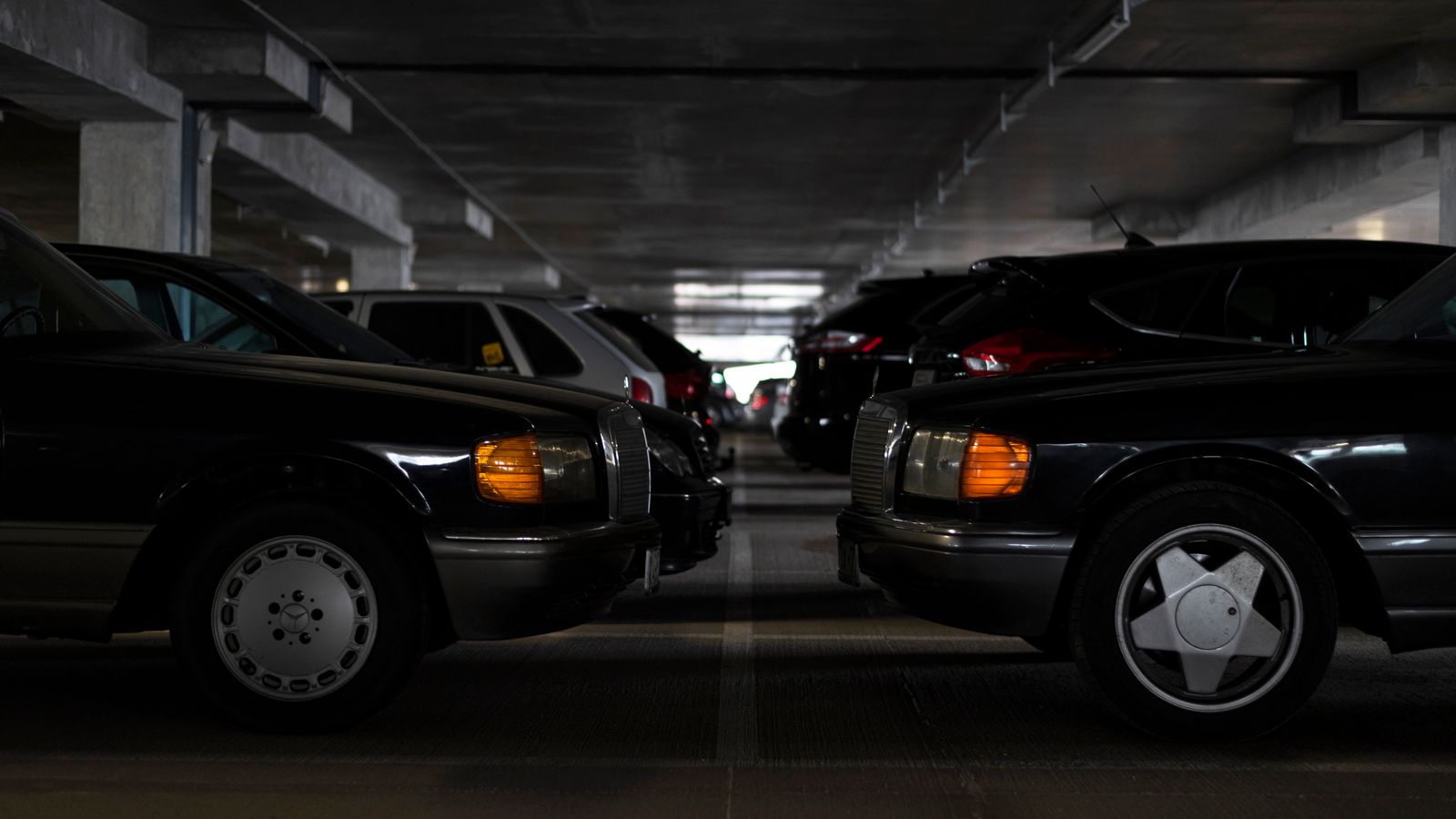 Classic cars parked in an indoor parking garage with muted lighting.