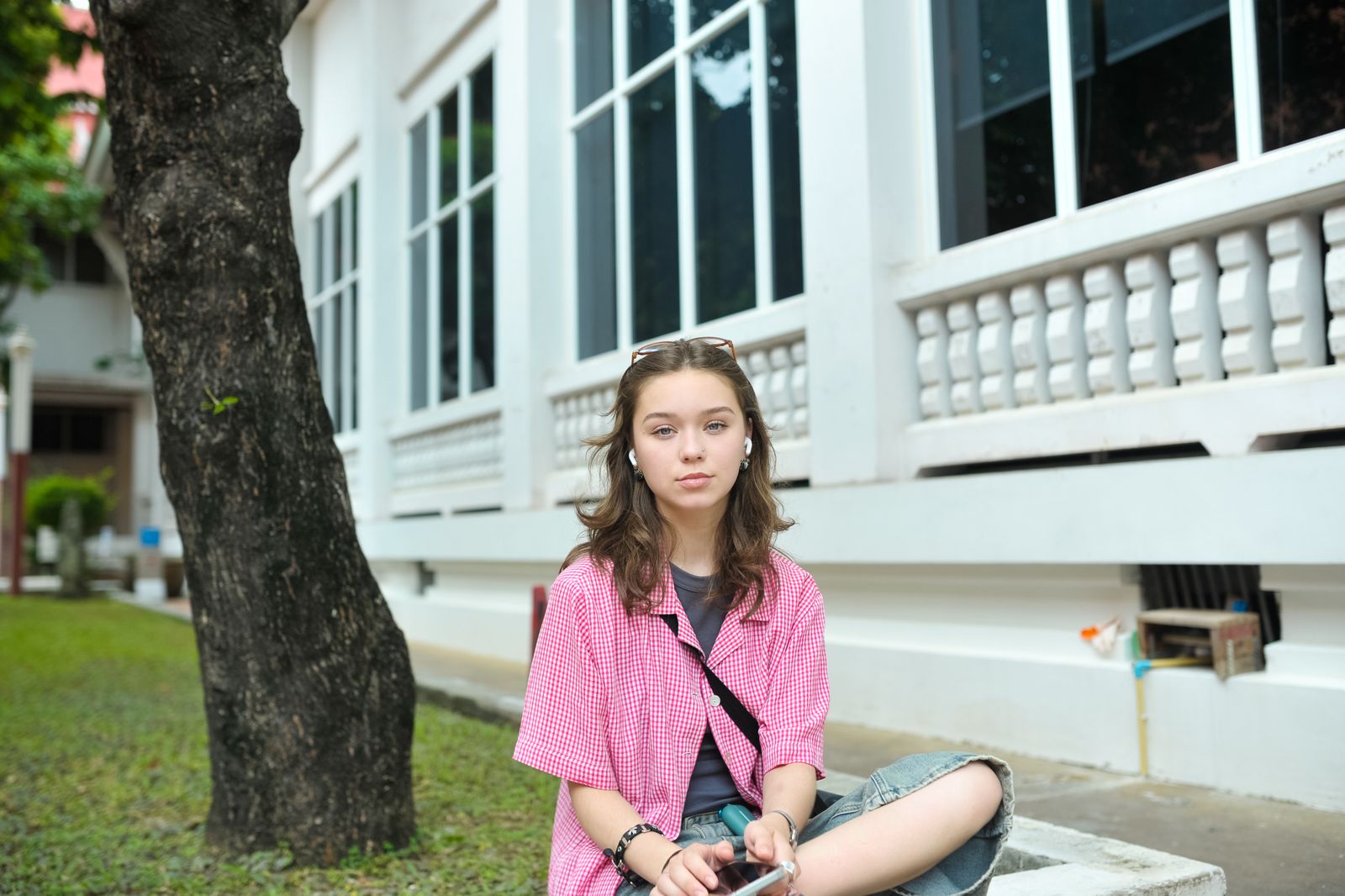 A young woman sitting casually outside a building, enjoying a moment of relaxation.