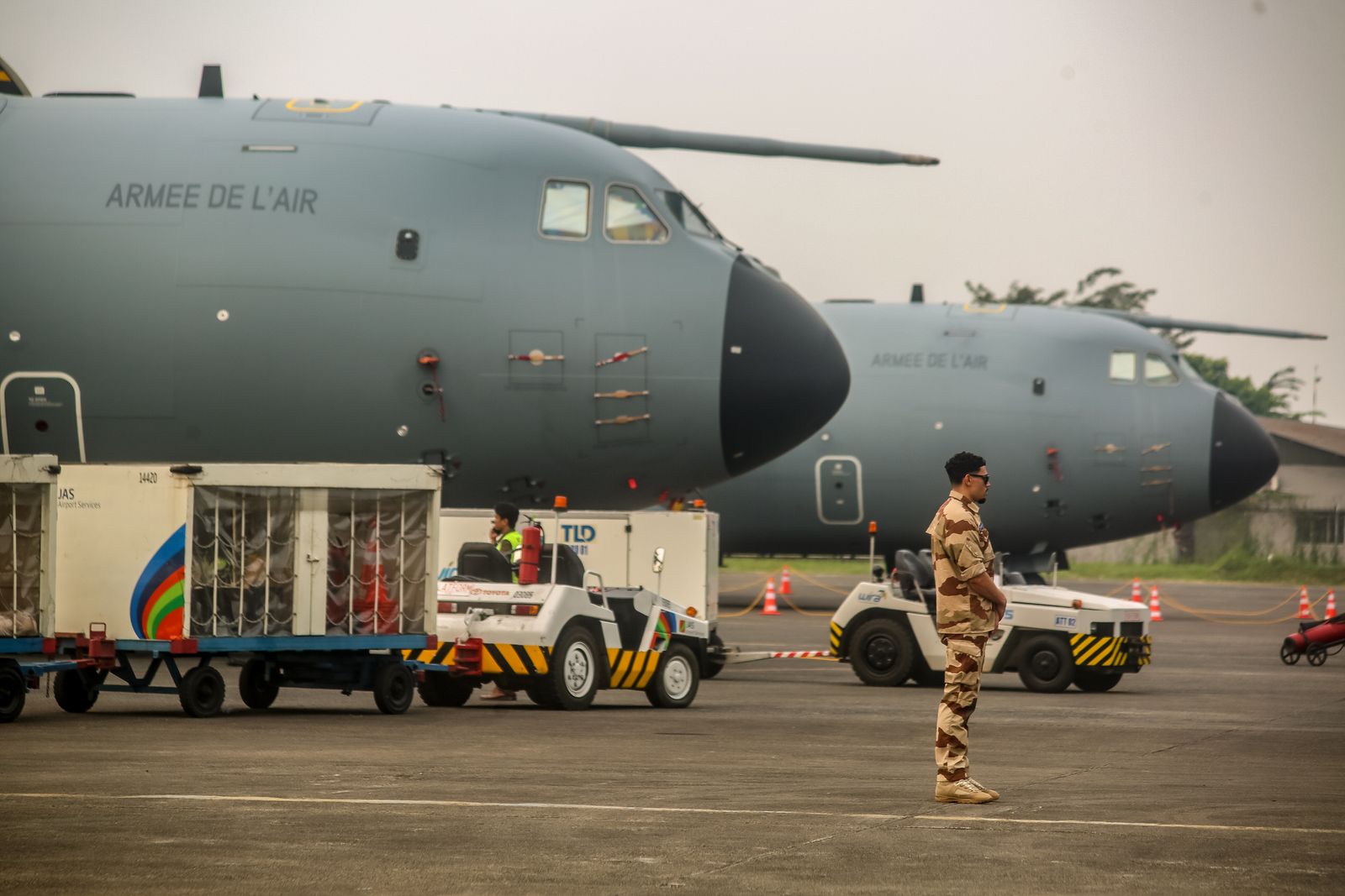 Military personnel near French Air Force planes at an airfield. Cargo loading in progress.