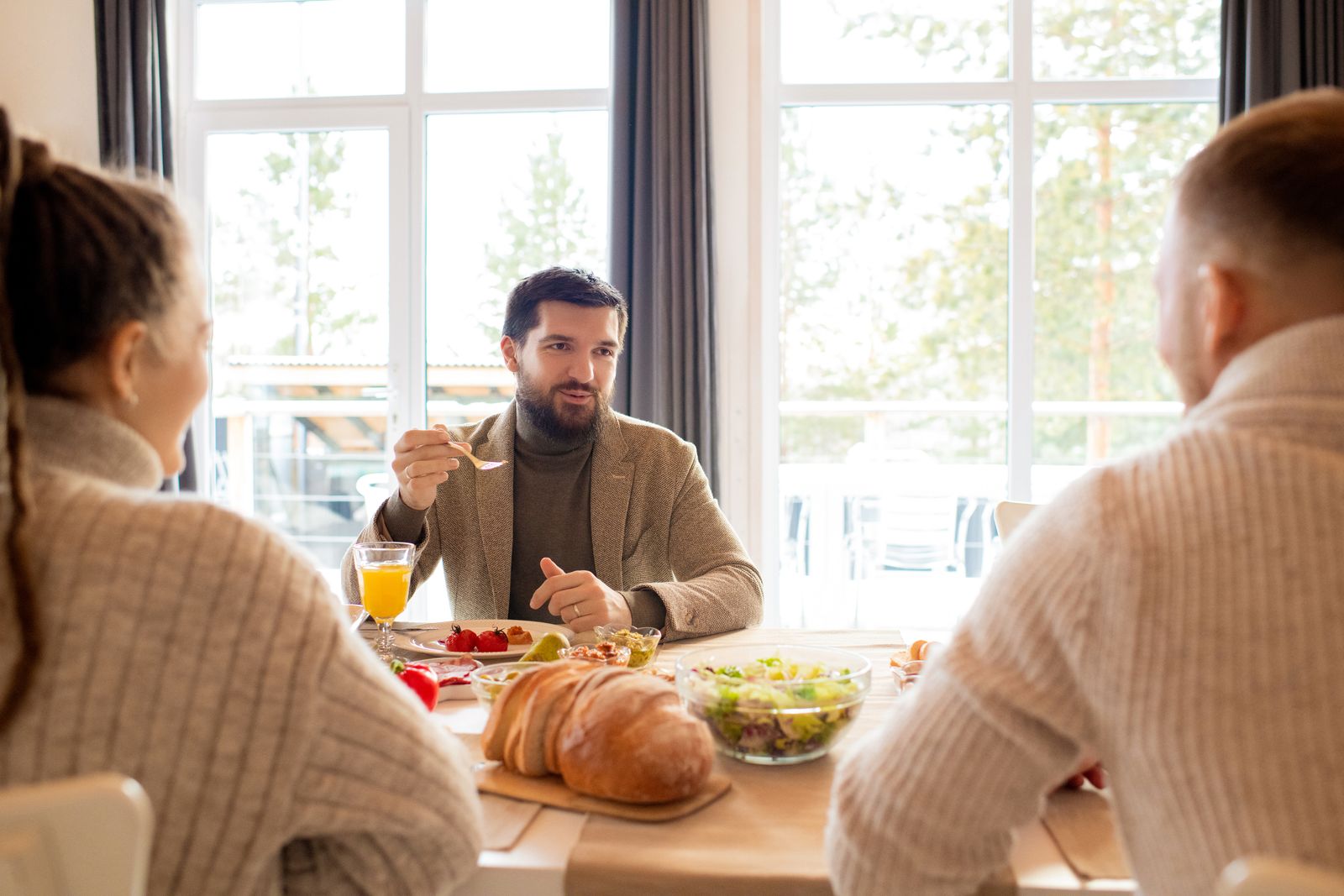 Adults having a warm indoor breakfast together with pastries and juice.