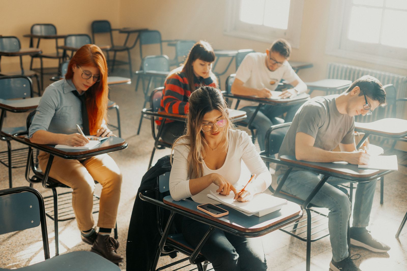 Group of students focused on writing during class in Buenos Aires classroom.