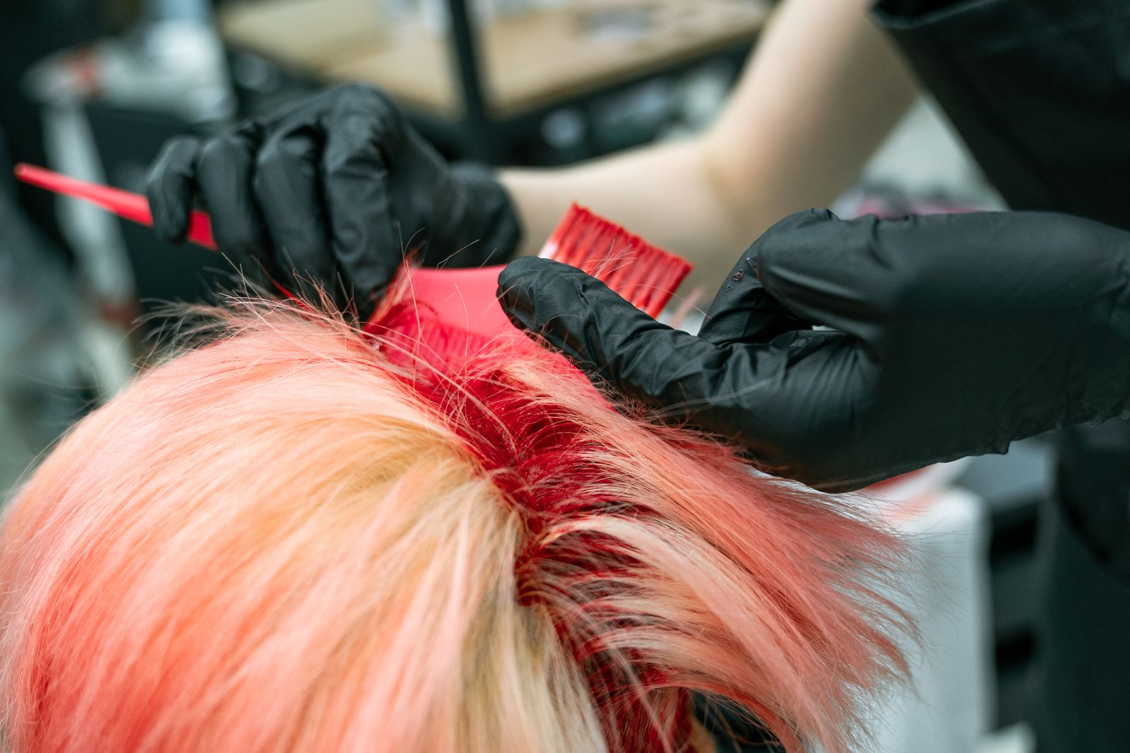 Close-up of vibrant hair coloring process with gloved hands applying dye.