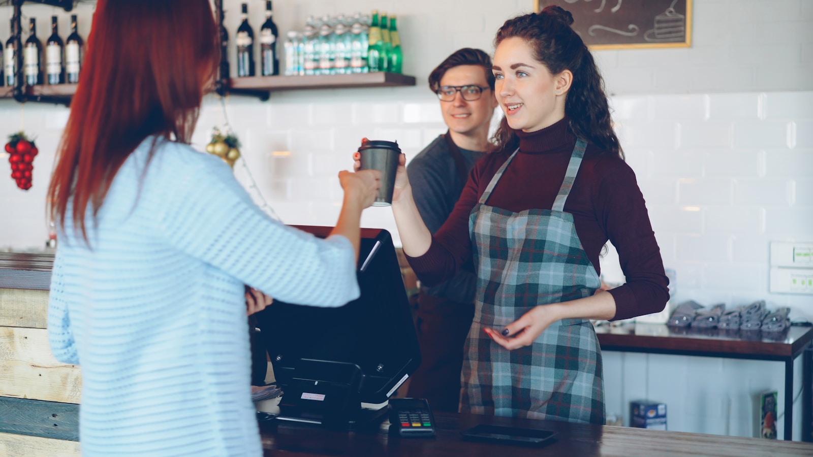 A barista handing coffee to a customer at the counter.