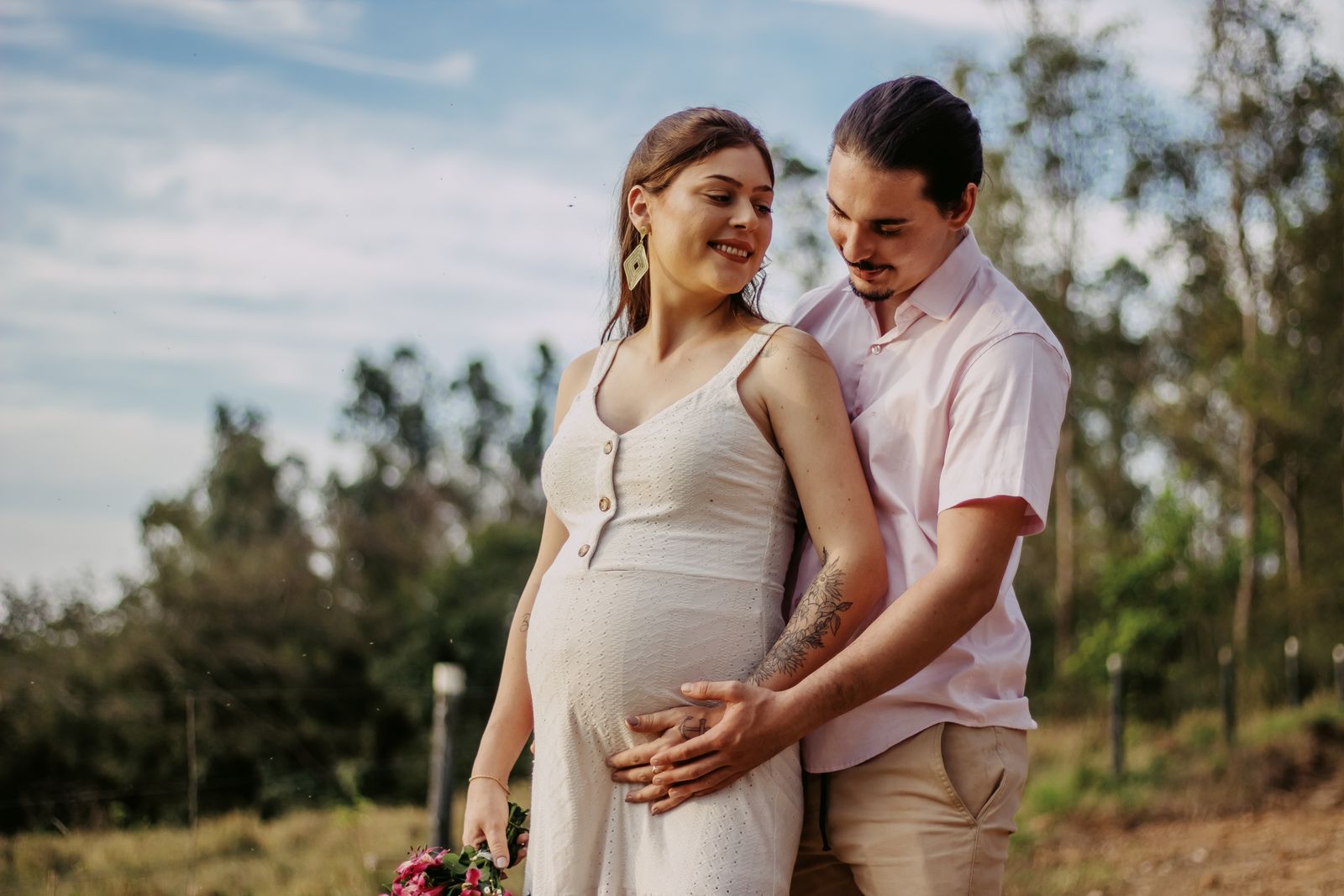 A joyful couple expecting a baby, embracing outdoors, showcasing love and anticipation.