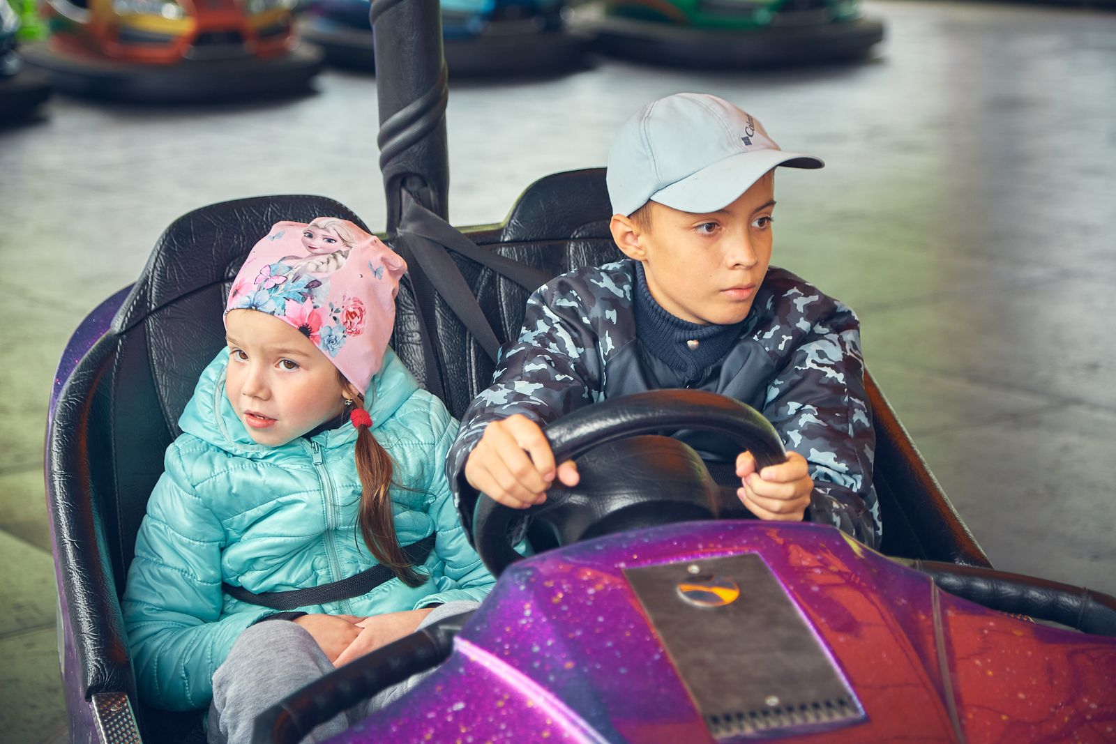 Two kids having fun driving a bumper car ride at an amusement park. Exciting and playful moment captured.