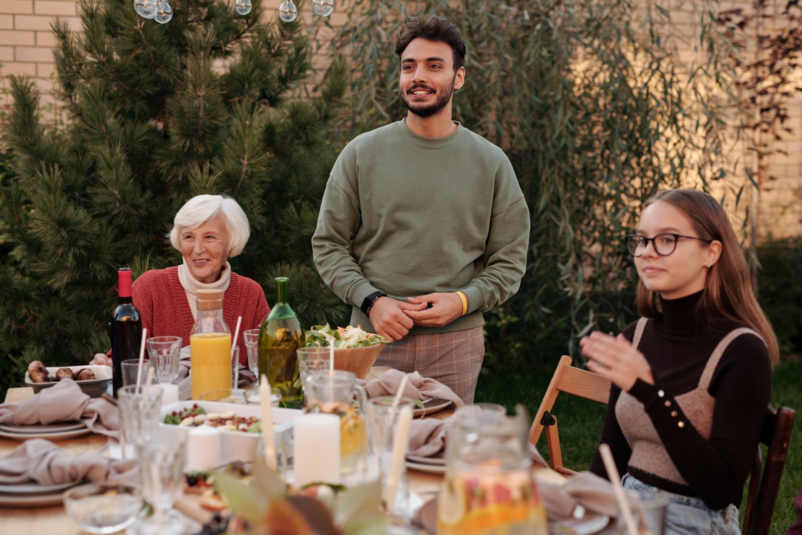 Cheerful family members having dinner party and spending time together in backyard in daytime