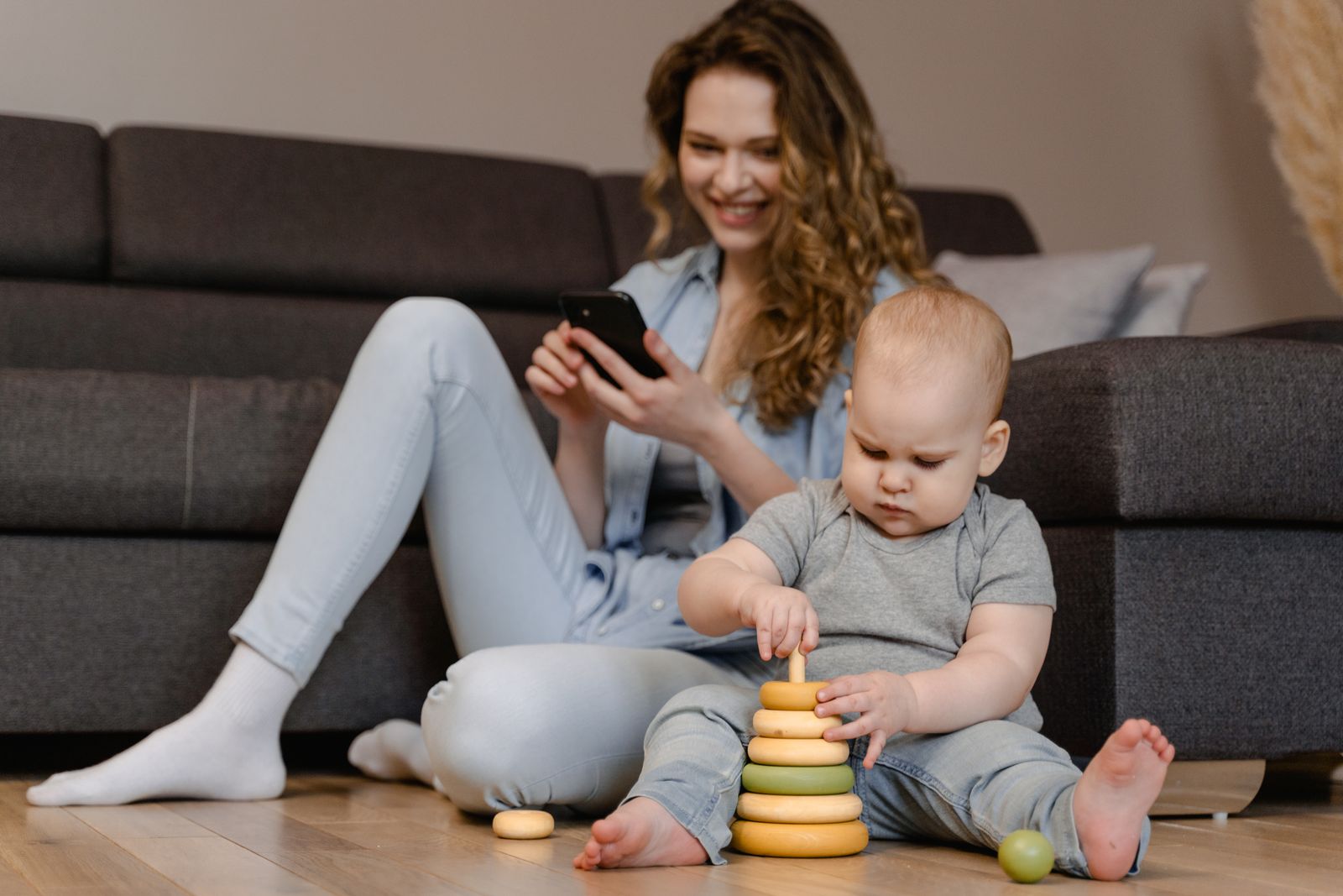 Mother and toddler engaged in playtime with toys on the floor at home.