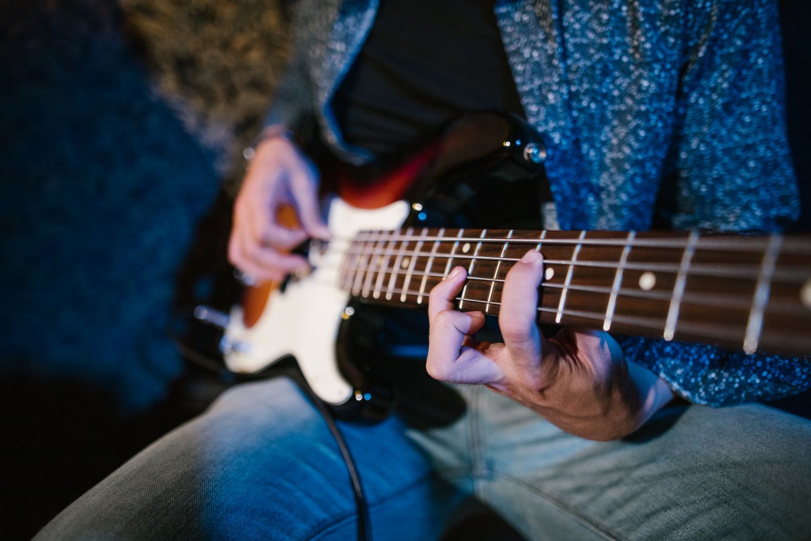 Focused shot of a guitarist strumming strings on an electric guitar during a performance.