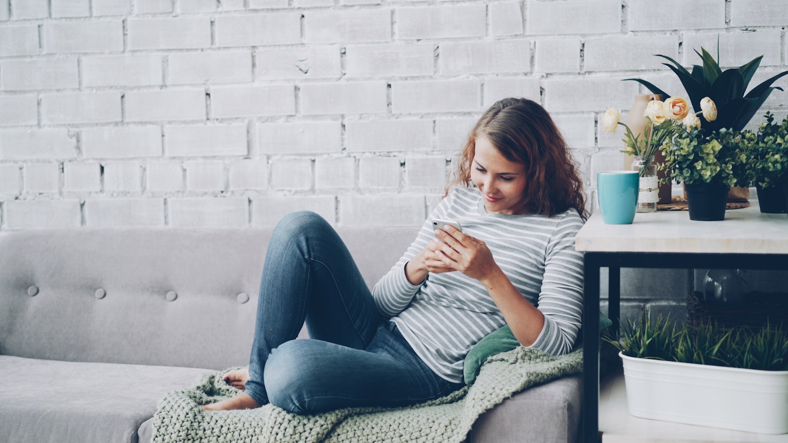 Young woman using smartphone on sofa