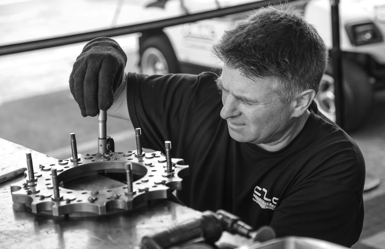 grayscale photo of man fixing gear