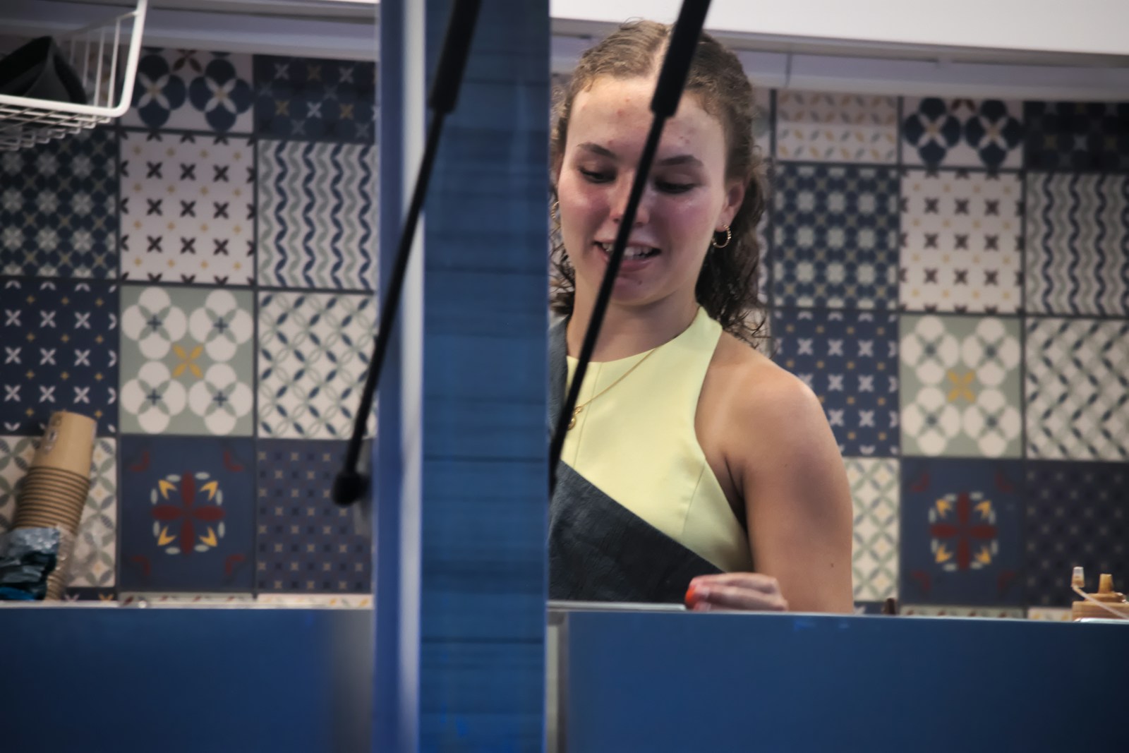 Young woman in yellow top behind a blue counter.