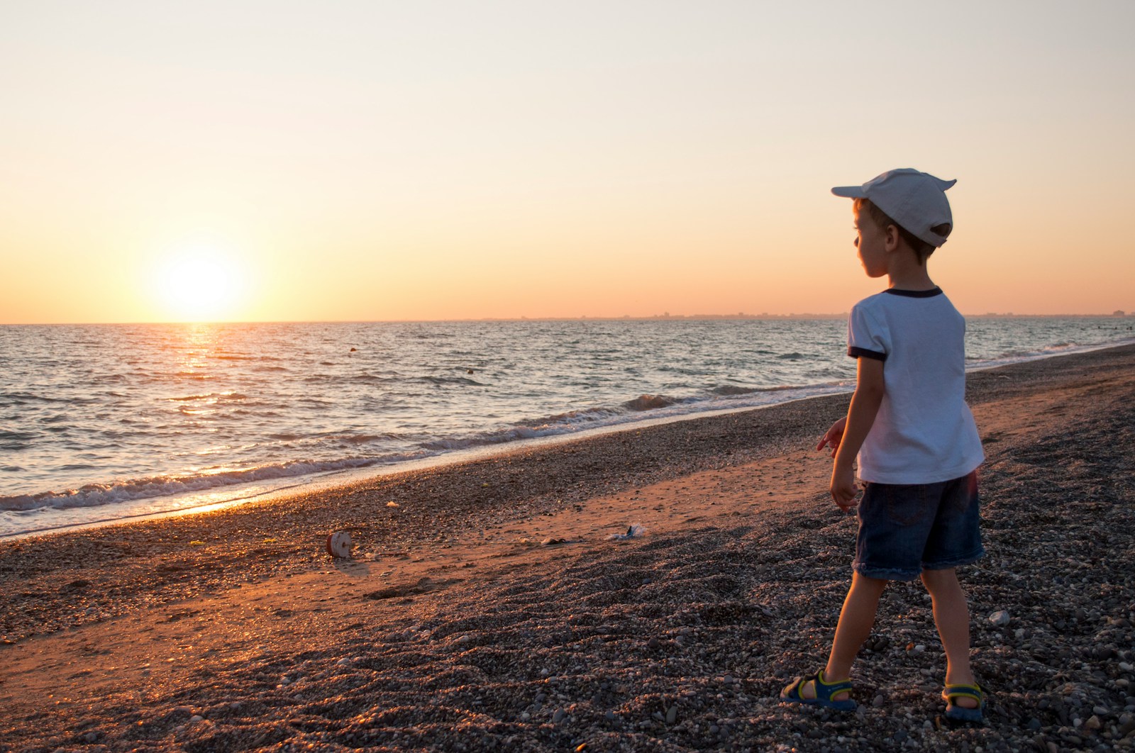 a young boy standing on top of a sandy beach