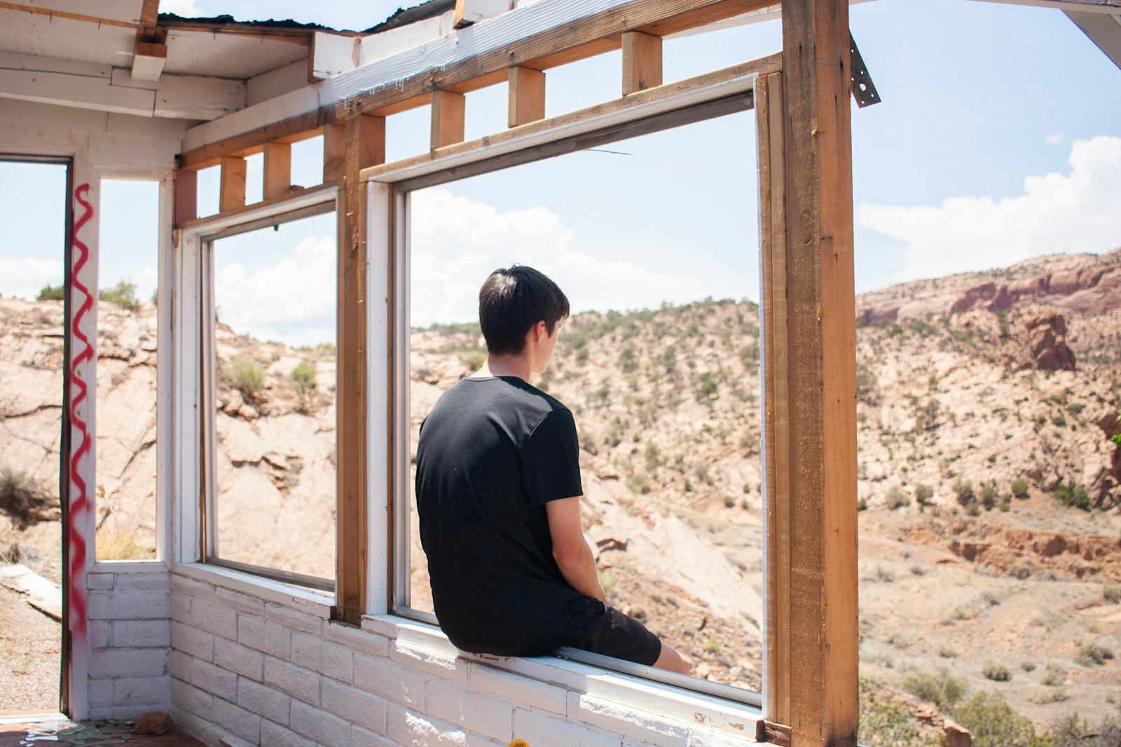 a man sitting on a window sill looking out a window