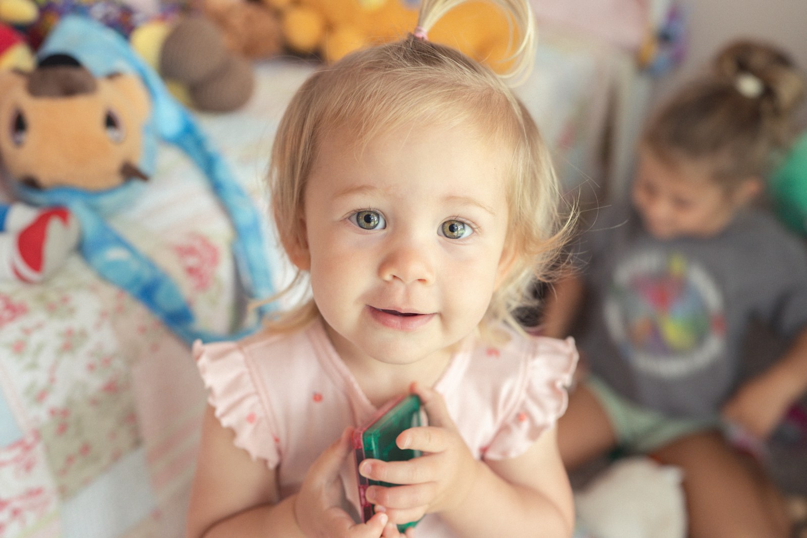 Young girl holding a green toy with stuffed animals.