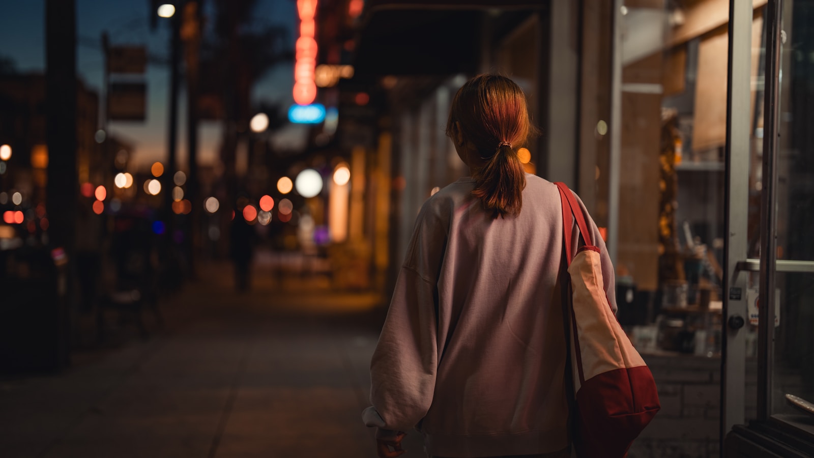 a woman walking down a street at night