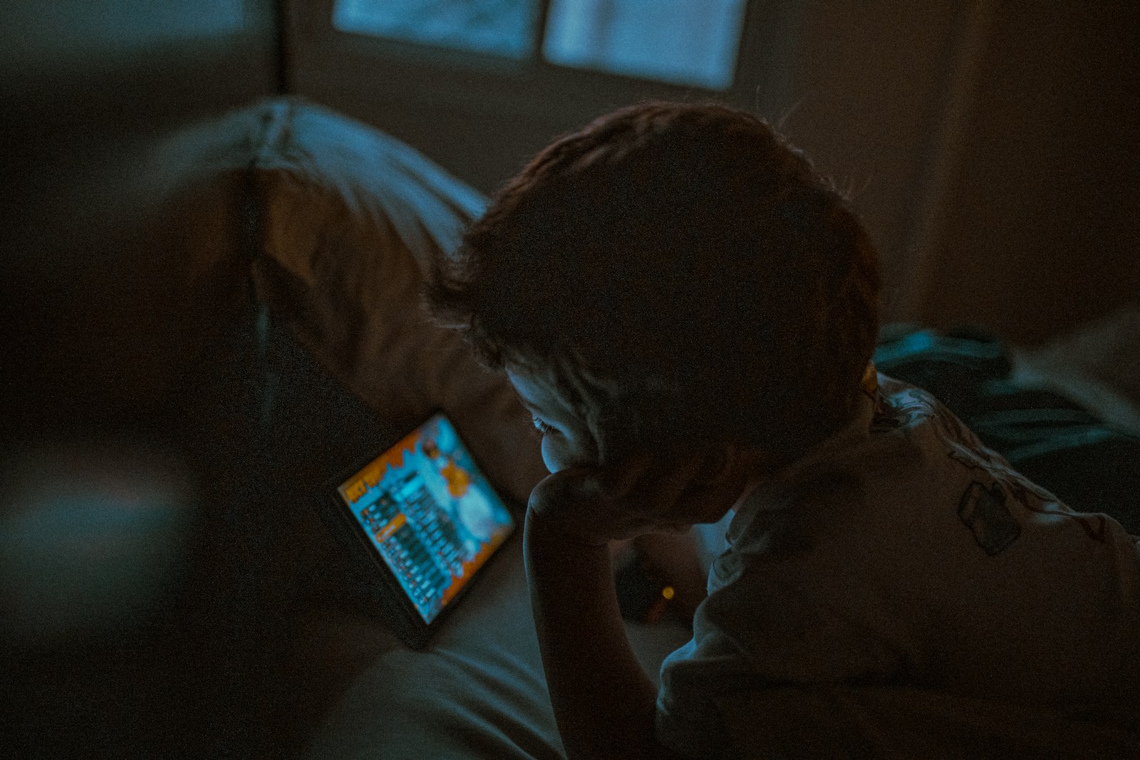 Child watching tablet in dark room
