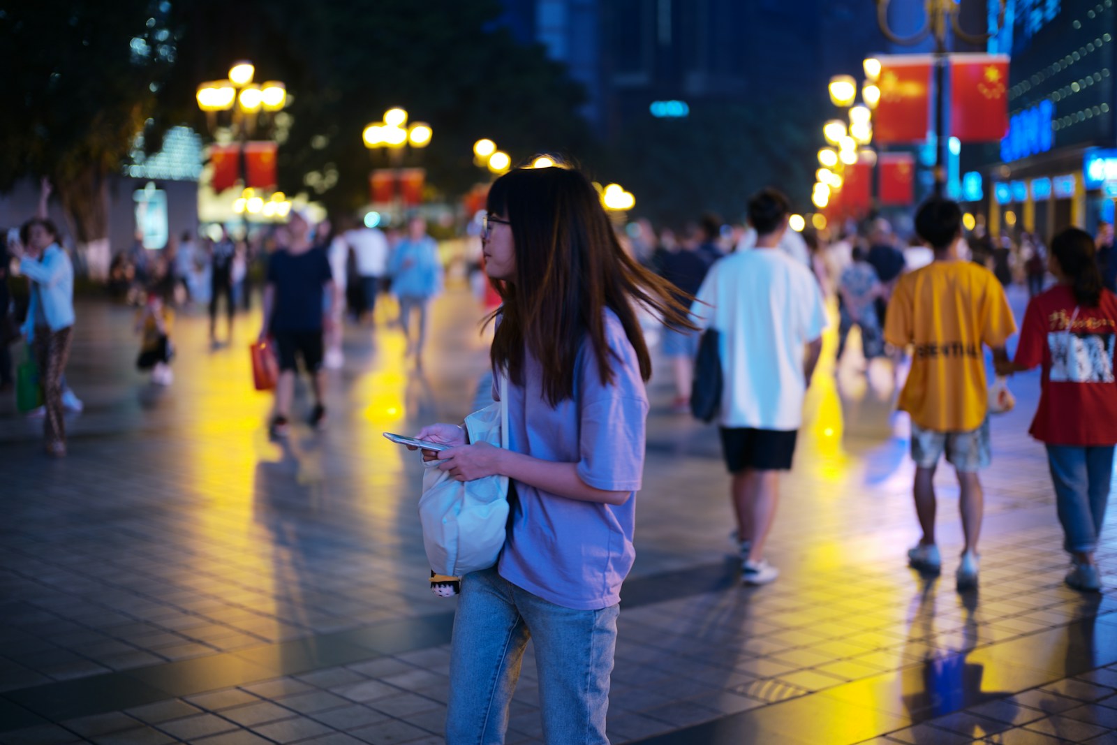 Young woman walking on a busy city street at night.