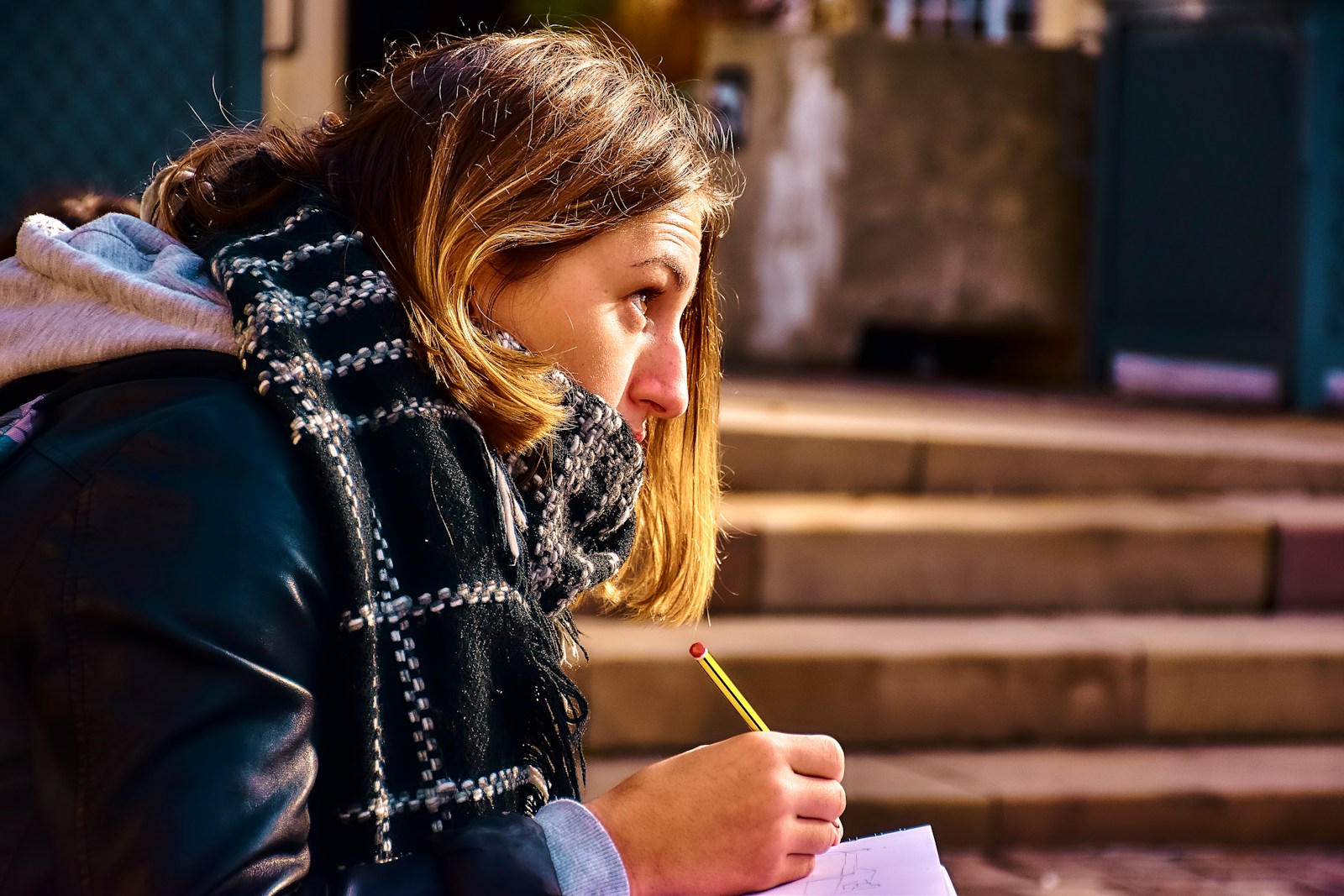 Woman writing on paper with a pencil outdoors