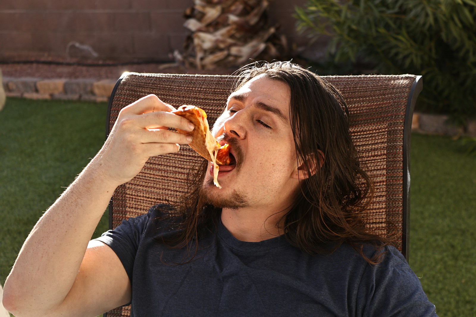 Man enjoys a slice of pizza.