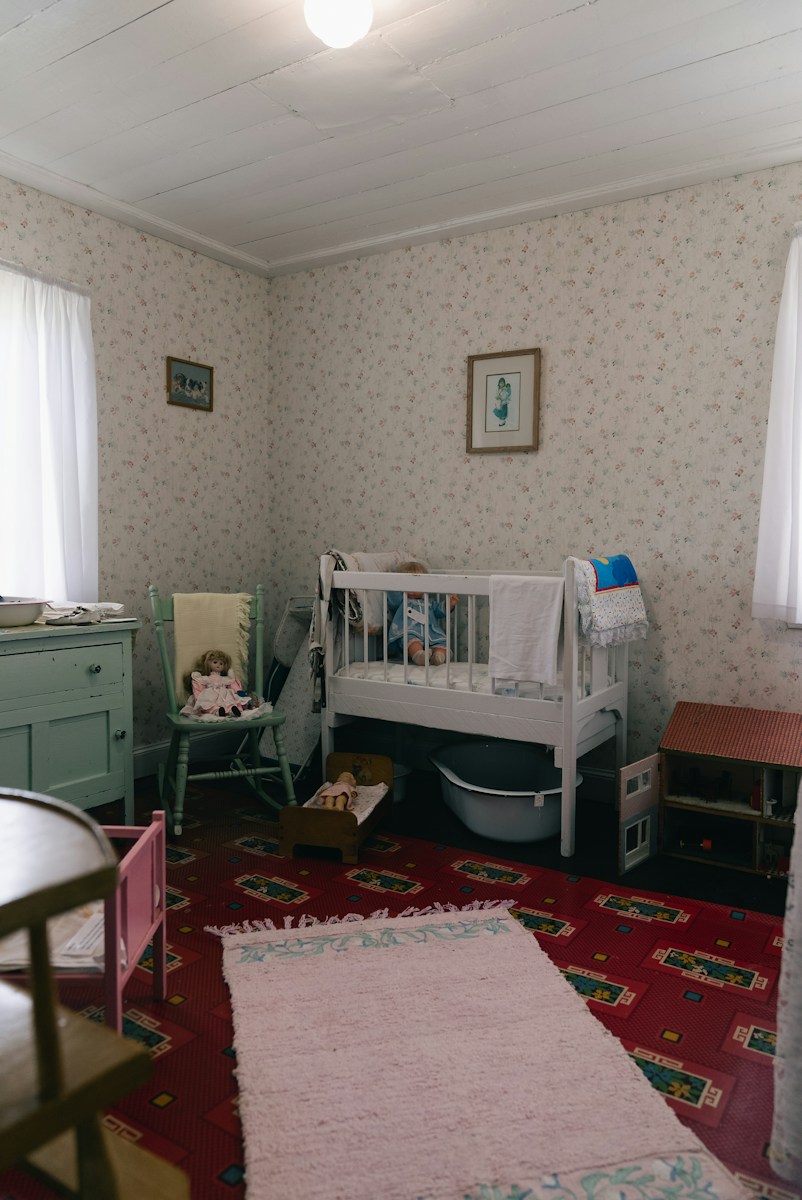 An old-fashioned child's room with a crib and patterned wallpaper
