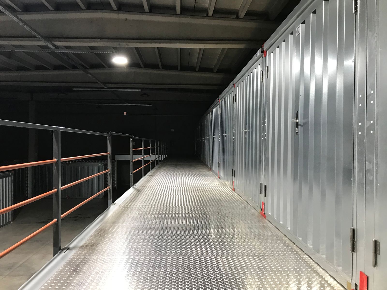 Empty industrial hallway with steel lockers and railing in a warehouse.