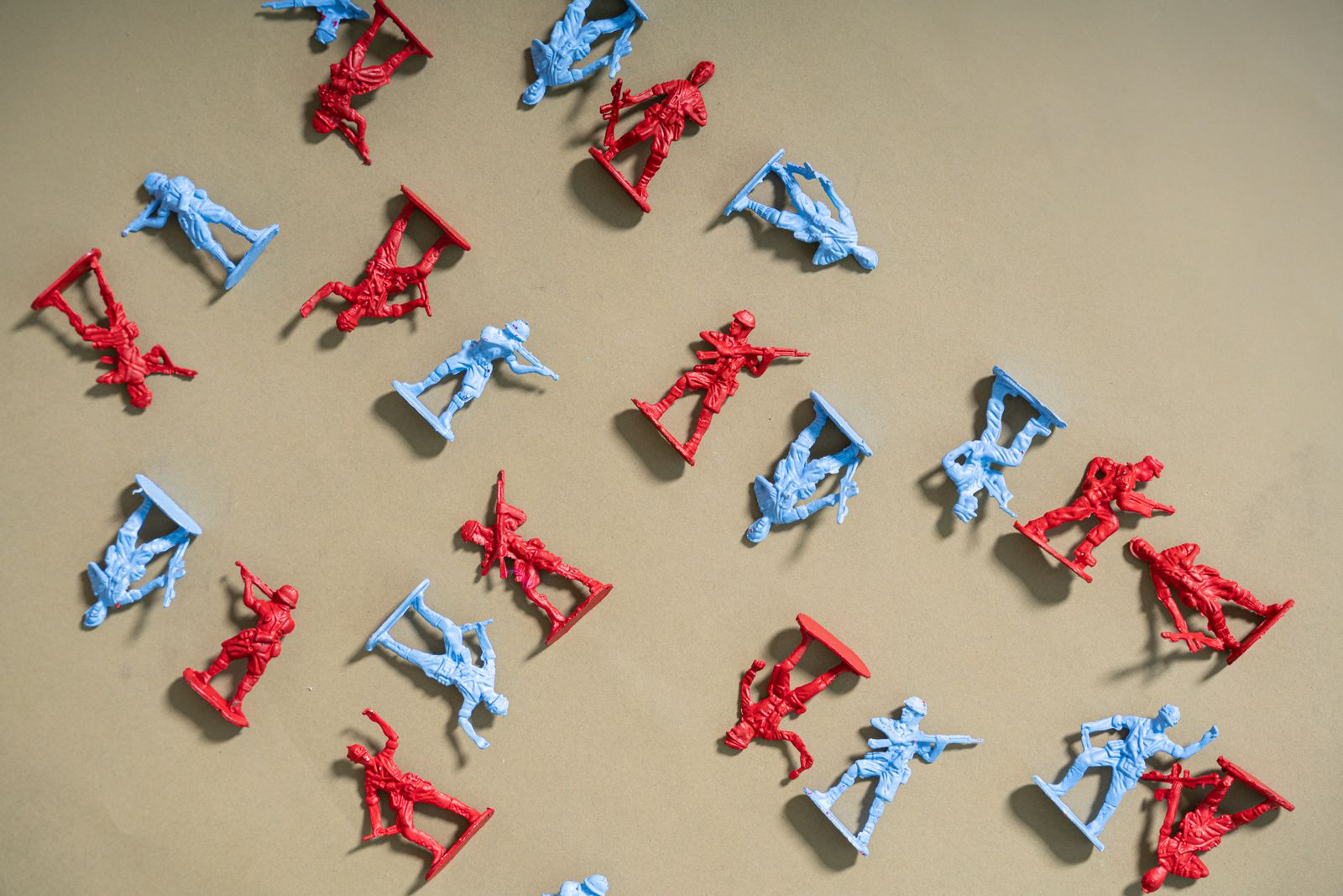 Red and blue toy soldiers arranged on a beige background, artistic flat lay.
