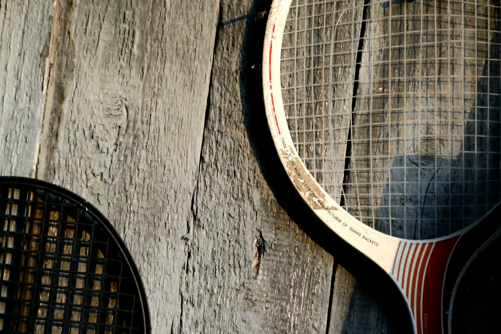 Two vintage tennis racquets leaning against a wooden wall