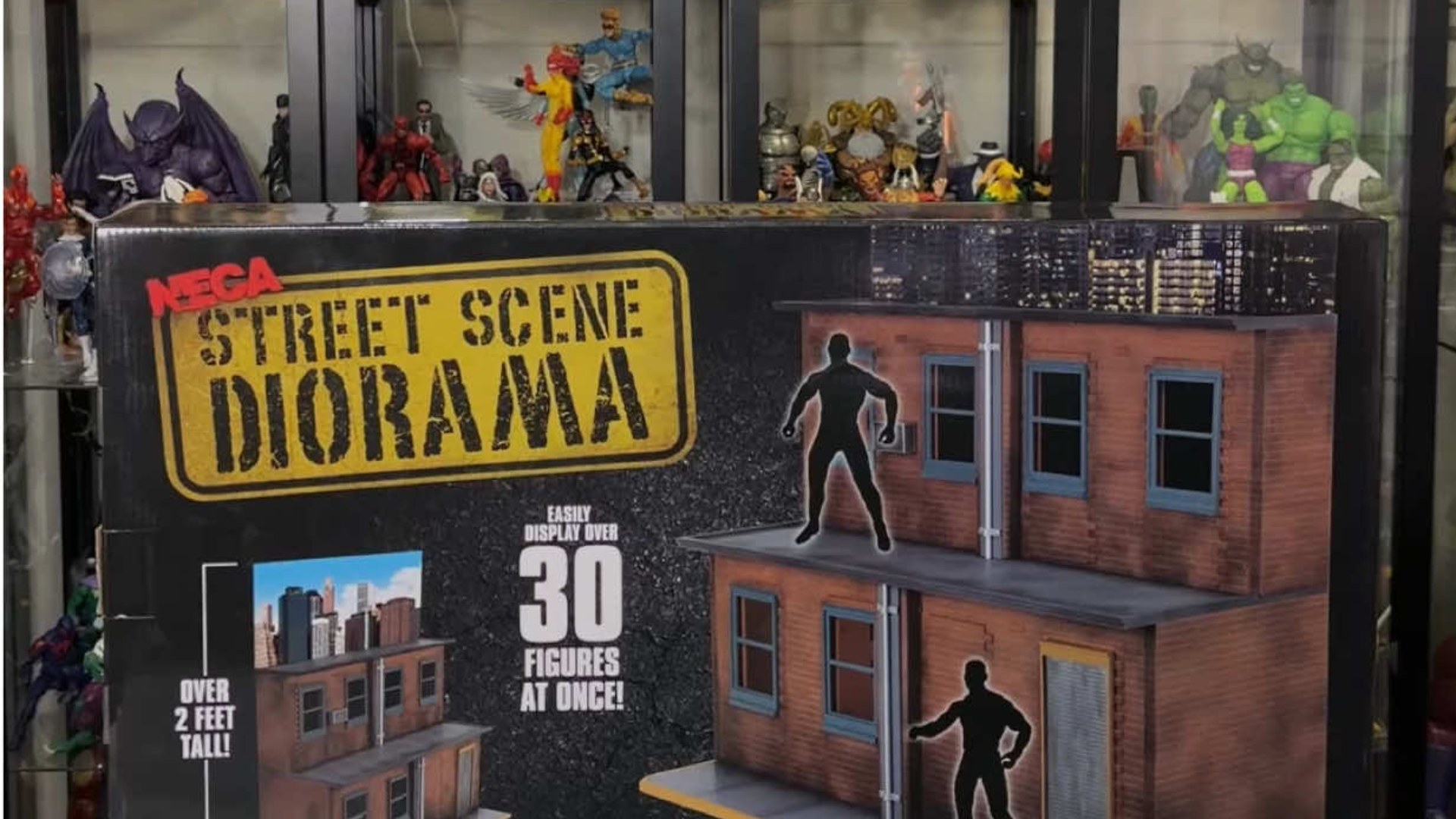 NECA street scene diorama box in front of an action figure display wall