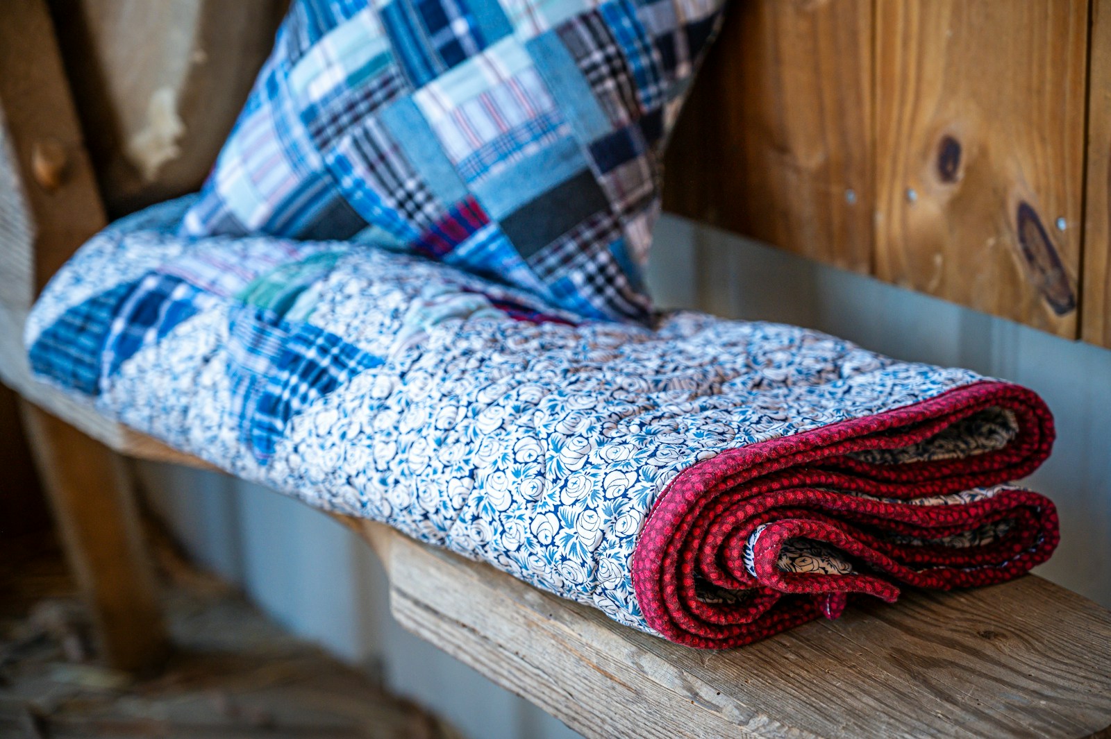 A quilt and pillow are resting on a wooden shelf