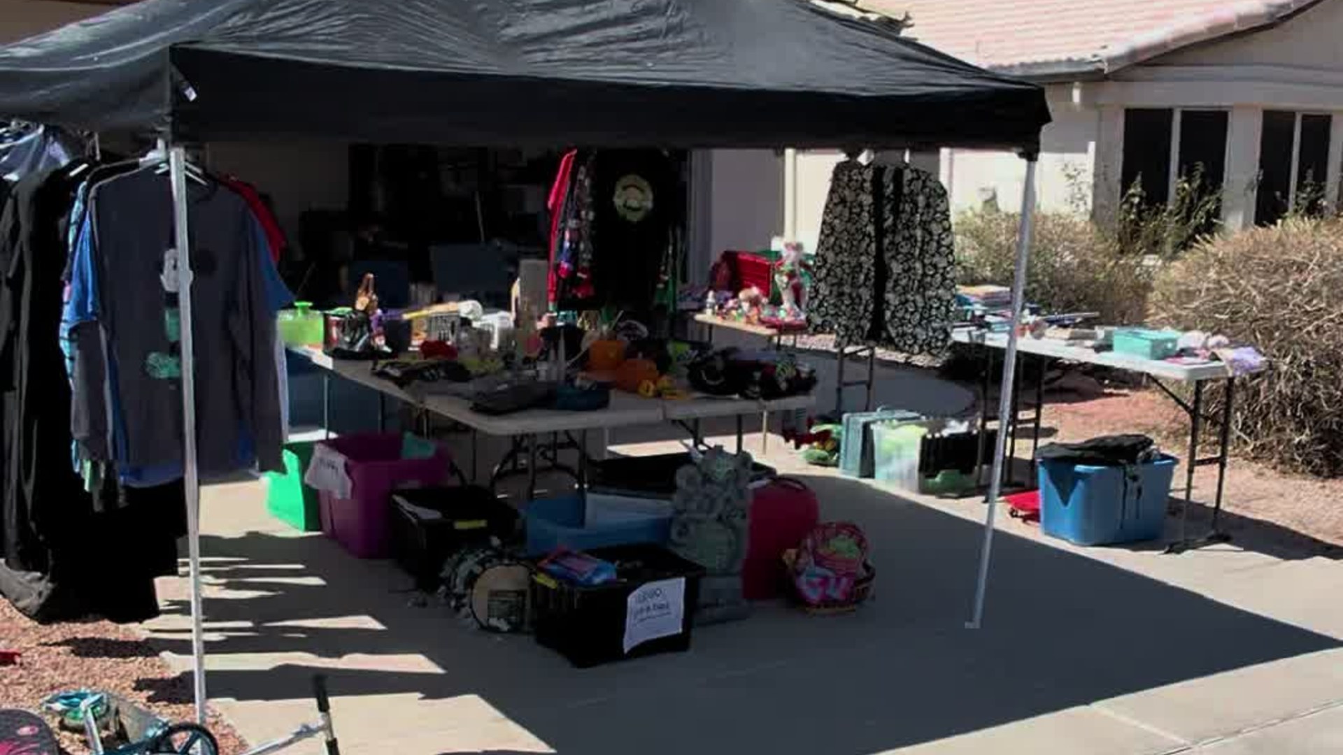 Tables of items under a canopy at the yard sale where a shopper found a Halo helmet and Jack Skellington jacket