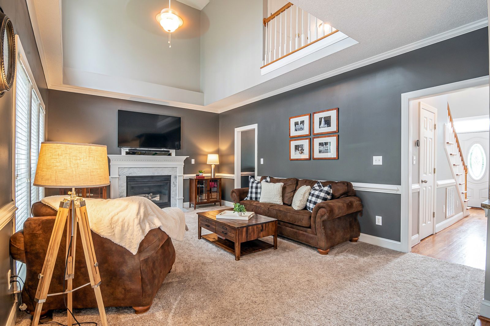 Spacious and elegant living room featuring a cozy fireplace, modern furniture, and warm lighting.