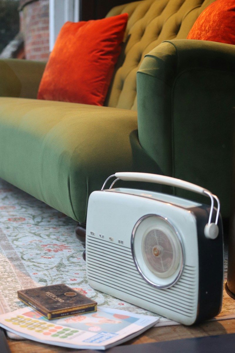 Vintage radio sits on a rug near a green sofa